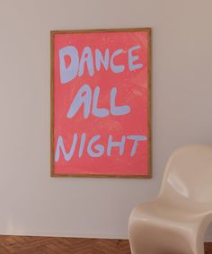 a painting that says dance all night hanging on the wall next to a white chair