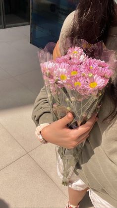 a woman holding flowers in her hands on the sidewalk