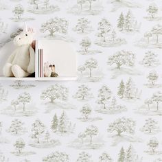 a white teddy bear sitting on top of a book shelf next to a wallpaper