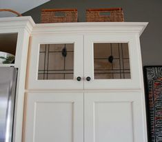 a white cabinet with two baskets on top of it and a refrigerator in the background