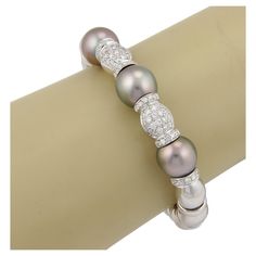 This is a stunning Estate bracelet, it is well crafted from 18k white gold with a high polished finish. It features a flex style cuff bracelet with long beaded design and ring links, the front of the band has two part bead with ring links adorned with sparkling diamonds and three shimmering grey South Sea pearls 11.5mm each. The diamonds are a total weight of 80 points and are set in beautiful alternating pattern. Material: 18k white gold Measurement: inner circumference: 5.75" Front of band: 2.75" across x 0.46" wide x 0.46" high Diamond: 0.80 total carat weight Pearls: South Sea (appx 11.5mm each) Weight: 65.5 grams Diamond Bangles Bracelet, Cuff Bangle Bracelet, Fine Jewelry Bracelets, Diamond Bangle, South Sea Pearls, Sea Pearls, Pearl Grey, Cuff Bangles, Sparkle Diamonds