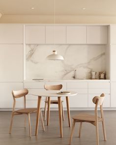 a white kitchen with marble counter tops and wooden chairs around a round dining room table