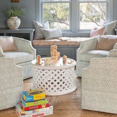 a living room filled with lots of furniture and pillows on top of a table next to a window