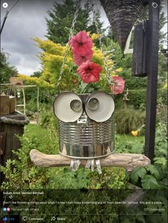 a tin can bird feeder with flowers hanging from it's side and eyes open