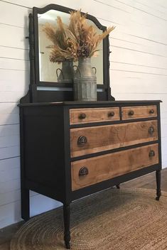 an old dresser with a mirror and vase on top is shown in front of a white wall