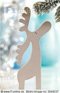 a wooden reindeer ornament sitting on top of a table next to a christmas tree