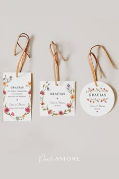 three tags with flowers on them hanging from clothes pins