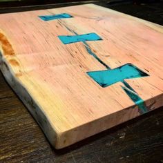 a wooden cutting board with blue arrows painted on the side and wood grain around it