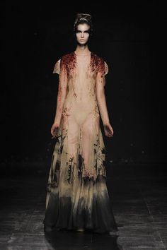 a woman is walking down the runway in a dress with blood all over her body