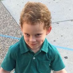 a young boy in green shirt standing on sidewalk