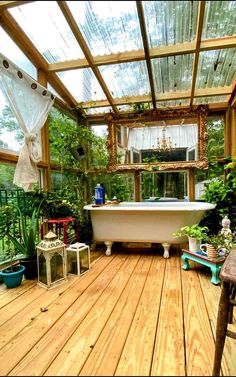 an outdoor bathroom with wooden floors and plants in the window sill, along with a white bathtub