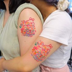 two women with matching tattoos on their arms and shoulder, both holding onto each other