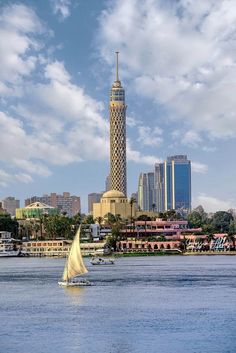 a sailboat on the water in front of a tall building