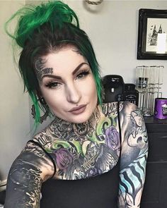 a woman with green hair and tattoos taking a selfie