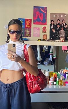 a woman standing in front of a counter holding a cell phone and wearing sunglasses on top of her head