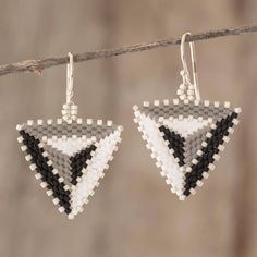 two pairs of earrings hanging from a string on a branch with beads and thread in the shape of triangles