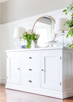 a room with a table, chairs and a mirror on top of the dressers