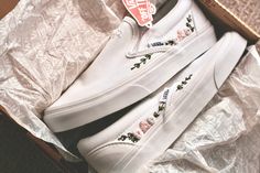 a pair of white vans with roses on the side in a cardboard box next to some wrapping paper