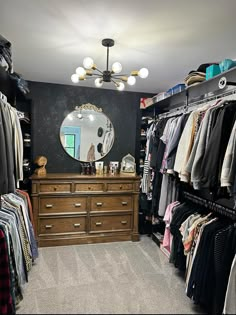 the closet is full of clothes and clothing hanging on racks, with a large mirror above it