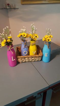 three vases with flowers in them are sitting on a table next to each other