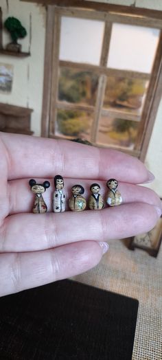 someone is holding five small beads that look like they are wearing hats and bow ties