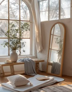 a large mirror sitting on top of a wooden floor next to a table filled with pillows