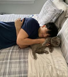 a man laying on top of a bed holding a cat