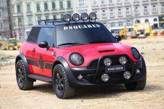 a red and black toy car with lights on it's roof sitting in the dirt