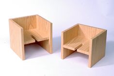 two wooden chairs sitting next to each other on a white surface with no one in it