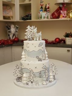 a three tiered cake decorated with white frosting and decorations on top of a table