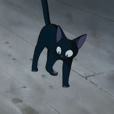 a black cat is walking on the ground with it's eyes wide open and looking at something