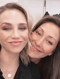 two women posing for the camera with one holding her head on another woman's shoulder