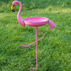 a pink flamingo bird feeder in the grass