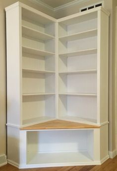 an empty white bookcase in the corner of a room