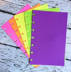 five different colored notebooks lined up on top of each other, with one empty notepad