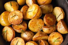 cooked potatoes in a pan with rosemary garnish on the side, ready to be eaten