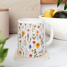 a mug with flowers on it sitting next to some fruit