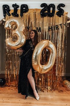 a woman standing in front of balloons and streamers with the number 30 on it