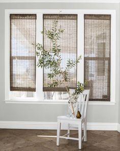 a white chair sitting in front of a window with blinds on the windowsills