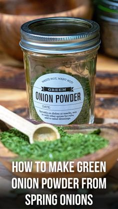 a jar filled with green onion powder on top of a wooden table next to a spoon