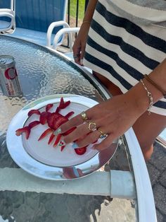 a woman is holding onto a plate with strawberries on it while wearing gold rings