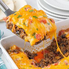 a casserole dish with meat and cheese being lifted from the casserole