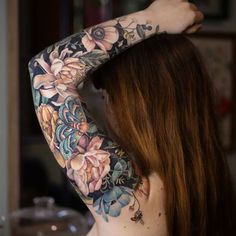 a woman with tattoos on her arms and shoulder is looking at the back of her head