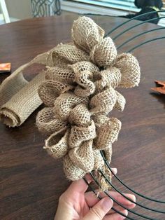 a hand holding a bunch of burlocked flowers on top of a wooden table