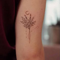 a woman's arm with a flower and moon tattoo on the back of her left arm