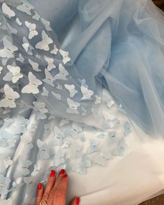 a woman's hand on the back of a blue dress with white flowers in it