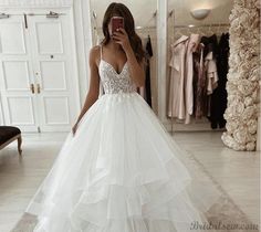 a woman taking a selfie in front of a mirror wearing a white wedding dress