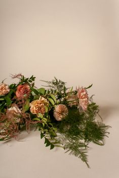 an arrangement of flowers and greenery on a white background