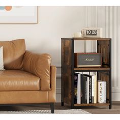 a brown leather couch sitting next to a book shelf with books on top of it