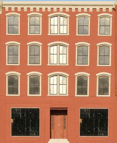 a red brick building with several windows and a fire hydrant in the foreground